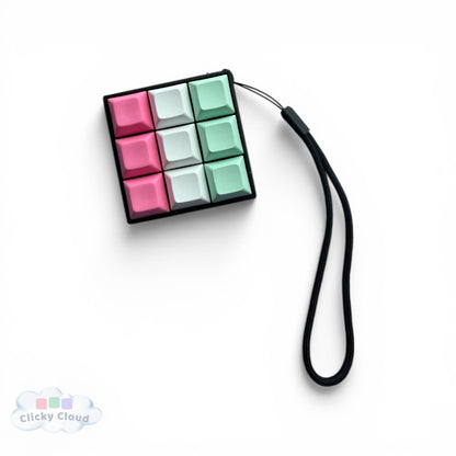Colorful key clicker keychain with a black strap on a white background