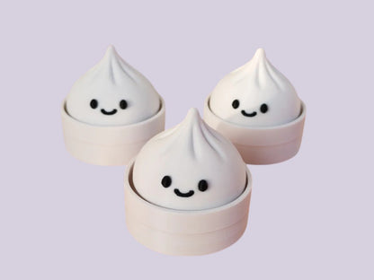 Three dumpling clickers with smiling faces on a light purple background