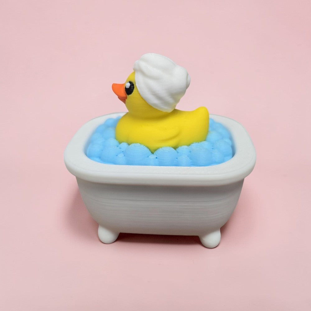 Yellow rubber duck clicker in a bathtub filled with blue bubbles on a pink background