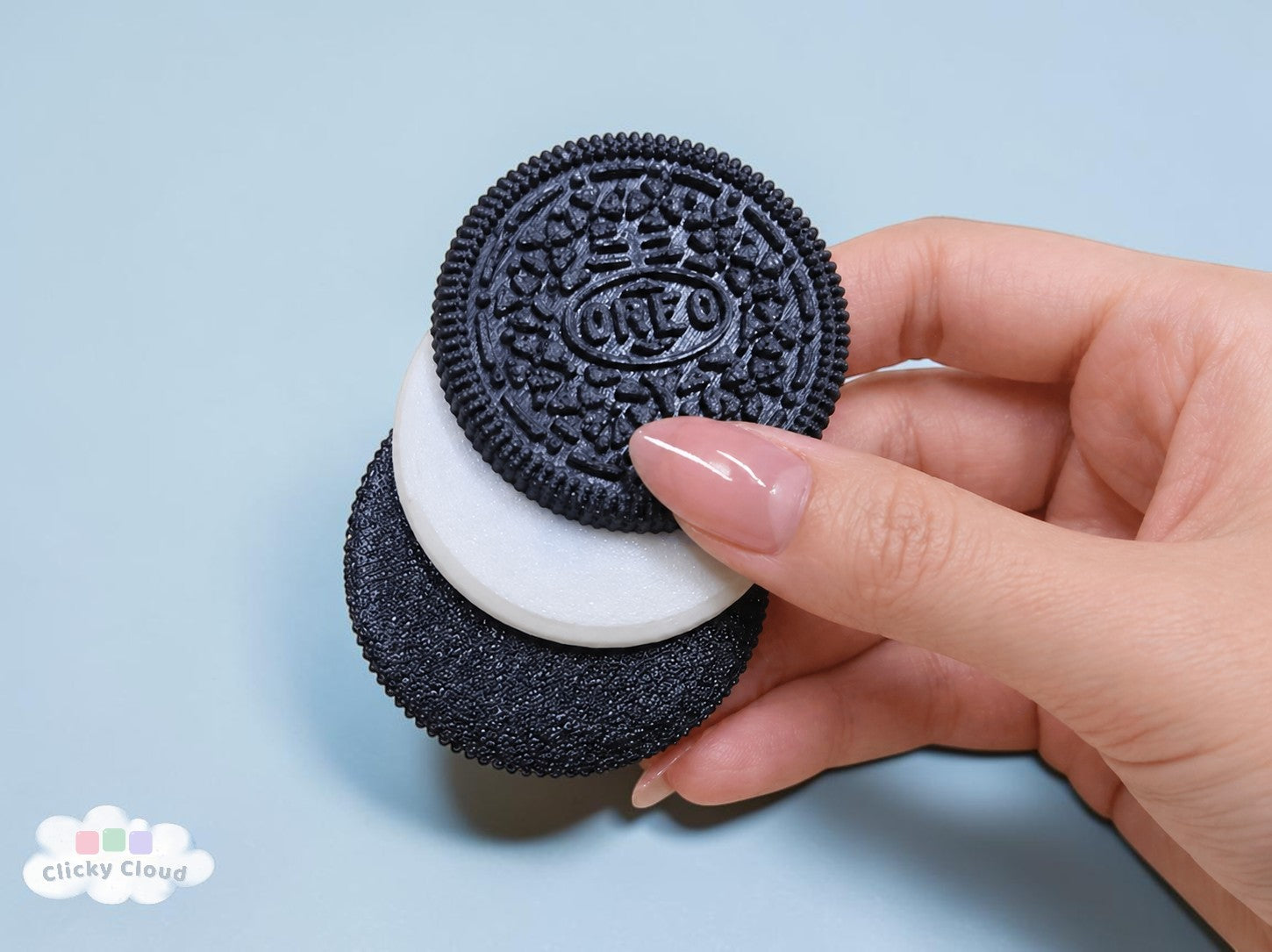 Hand holding two Oreo cookies against a light blue background