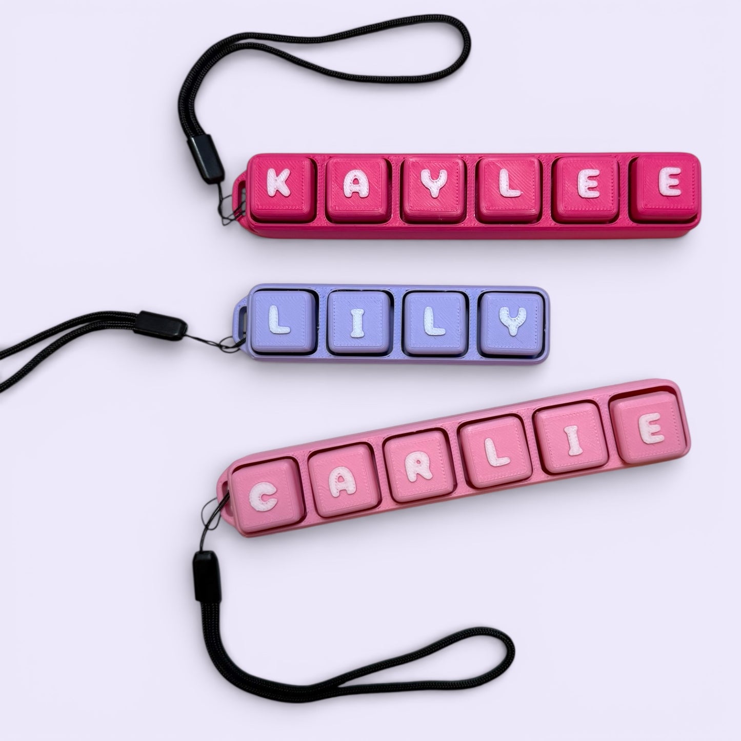 Three colorful name tags with letters spelling 'KAYLIE', 'LILLY', and 'CARLIE' on a light purple background.